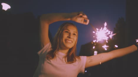 Lächelnd-Teenager-Mädchen-auf-der-Straße-bei-Nacht-mit-Wunderkerzen