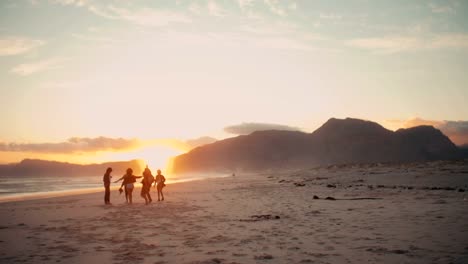 Silueta-de-Teen-amigos-bailando-en-la-playa-al-anochecer