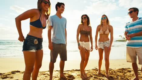 Gruppe-von-Freunden-hängen-am-Strand-bei-Sonnenuntergang