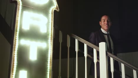 Gut-gekleidete-junge-Mann-geht-eine-Reihe-von-Treppen-in-einem-Nachtclub-und-lächelt-in-die-Kamera