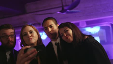 A-group-of-well-dressed-friends-in-a-nightclub-taking-selfies-with-a-cell-phone