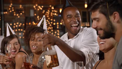 Friends-in-party-hats-celebrating-New-Year-at-party-in-a-bar