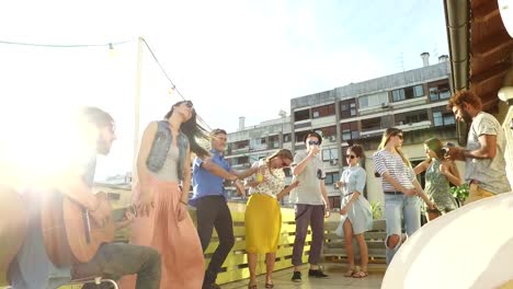 Happy-people-dancing-and-playing-guitar-at-the-rooftop-party-on-sunny-day