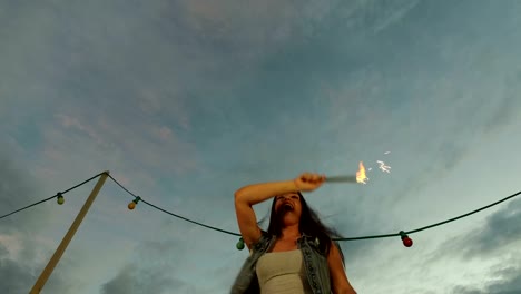 Low-angle-view-of-happy-woman-jumping-with-firework-candle