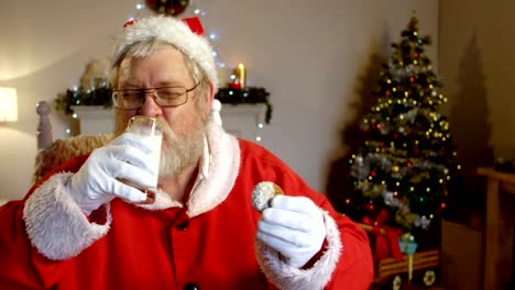 Santa-Claus-am-Stuhl-zu-entspannen-und-mit-süßen-Speisen