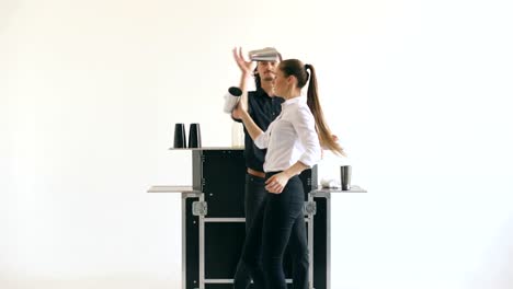 Professinal-bartender-man-and-woman-juggling-bottles-and-shaking-cocktail-at-mobile-bar-table-on-white-background