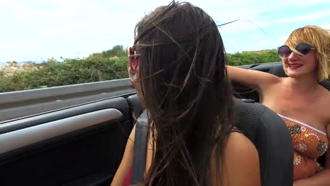 Two-attractive-women-riding-in-cabriolet-along-dalmatian-coast