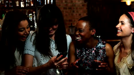 Friends-using-smartphone-at-bar-counter