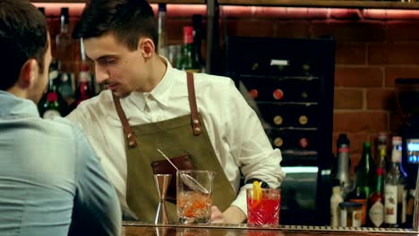 Barman-preparando-cócteles-para-un-cliente-y-a-la-espera-de-su-reacción