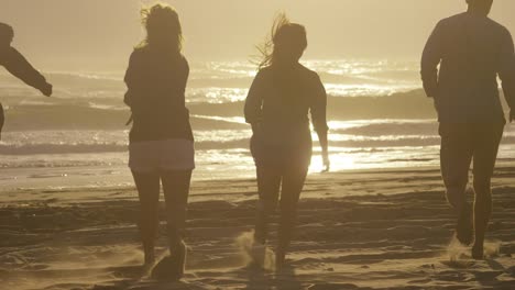 Amigos-corriendo-al-océano-al-atardecer-en-cámara-lenta