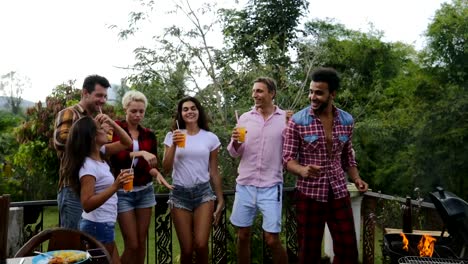 Young-People-Dancing-While-Latin-Man-Cooking-Barbecue-Friends-Group-Cheerful-Gathering-On-Summer-Terrace-Having-Party