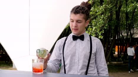 bartender-makes-mixed-drink-on-background-nature,-bar-worker-topped-up-rom-into-glass-with-ice-cubes