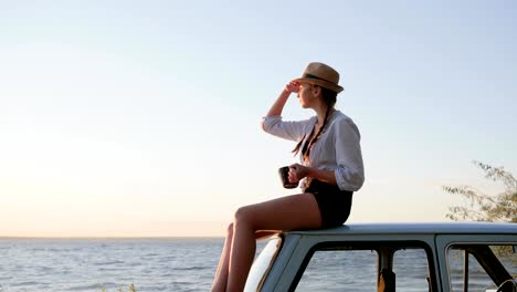 Tasse-Kaffee-in-der-Hand-der-Mädchen-sitzen-auf-dem-Dach-der-Oldtimer,-Tea-Time-für-junge-Frauen-auf-Oldtimer-Automobil