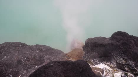 Boiling-Heißwasser-aus-Thermalquellen-in-den-Bergen-mit-Bäumen-von-Japan,-Becken-mit-heißem-Wasser,-Dampf-kochendem-Schlamm-Überoberseite-des-Teiches-Flut-Geysir.-Schwefel-Kessel-Dan