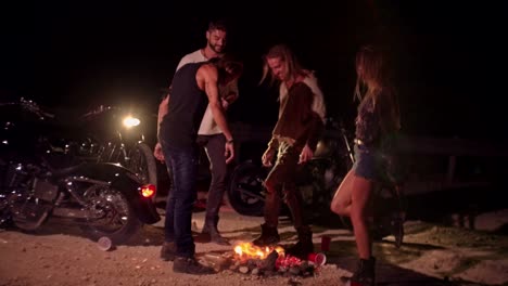 Young-drunk-rebel-friends-with-motorcycles-dancing-around-campfire