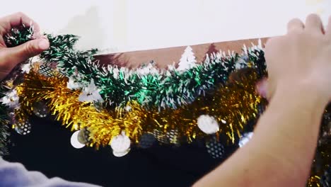 4K-Hands-of-person-hanging-Christmas-decoration-on-the-wall.-Vintage-toned-footage.