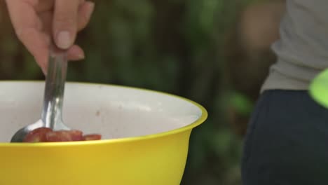 Young-happy-kids-preparing-eating-lunch-pasta-in-summer-camp-outside-on-sunny-day-in-park-serving-food-from-pot-pan-slow-motion