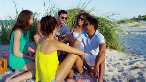 Multi-ethnic-friends-playing-guitar-and-enjoying-picnic