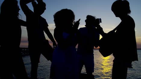 Silhouette-des-Menschen-tanzen-Gitarre-spielen-am-Strand