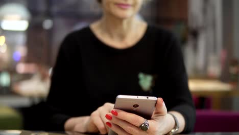 Eine-Frau-mittleren-Alters-nutzt-Mobile-Telefone-in-einem-Café.