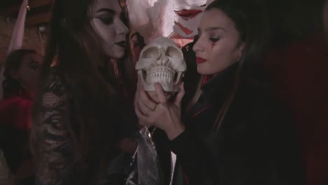 Young-women-in-scary-costumes-licking-skull-at-Halloween-party