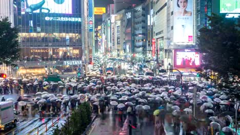 Timelapse-nocturno-de-turista-con-paraguas-caminando-en-el-lapso-de-tiempo-de-Shibuya-cruce-Calle-esquina,-Barrio-Shibuya,-Tokio,-Japón-de-4-K