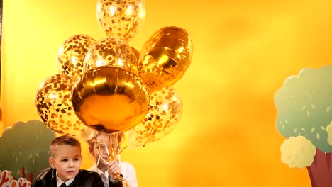 Happy-children-with-balloons-on-a-yellow-background-in-the-studio.