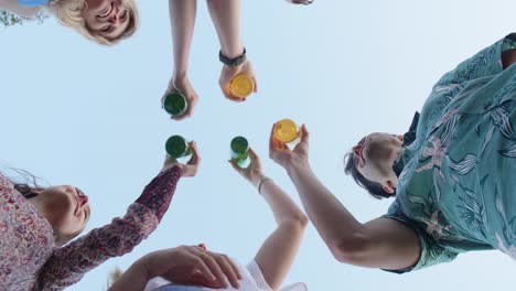 Bottom-up-view-of-friends-raising-their-beers-for-a-toast-at-a-party