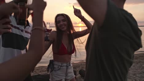 Unbeschwerte-junge-Leute-tanzen-am-Strand-bei-Sonnenuntergang