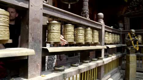 Woman-spins-prayer-wheels-in-Patan,-Durbar-Square,-Kathmandu-valley,-Nepal.