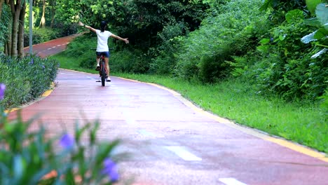 Bicicleta-de-mujer-feliz-del-montar-a-caballo-con-los-brazos-abiertos