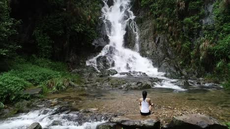 Asiatische-Yoga-Frau-Meditation-Wasserfall-in-Bergen