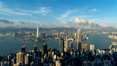 Lapso-de-tiempo-centro-de-la-ciudad-de-Hong-Kong.-Victoria-Harbour-desde-la-cima.-Distrito-financiero-de-ciudad-inteligente.-Rascacielos-y-altos-edificios.-Vista-aérea-con-cielo-azul.