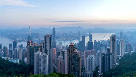 Zeitraffer-Nacht-zum-Tag.-Hong-Kong-Downtown-und-den-Victoria-Harbour.-Bankenviertel-in-smart-City.-Wolkenkratzer-und-Hochhaus-Gebäude-vom-Gipfel.-Luftbild-bei-Sonnenaufgang.