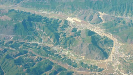 Hermosa-vista-a-través-de-la-ventana-del-avión,-avión-volando-por-encima-de-la-ciudad-en-las-montañas