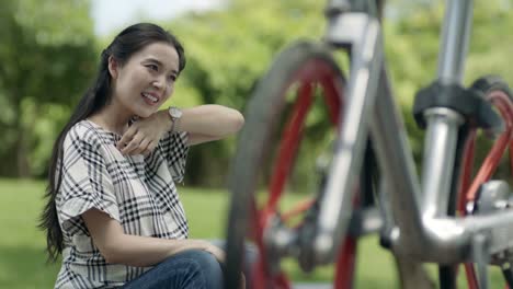 asiatische-Frau-sitzen-und-ausruhen-nach-dem-Radfahren-im-freien