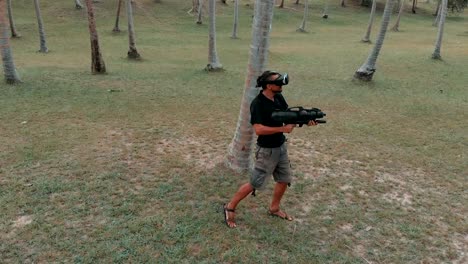 Man-with-weapon-playing-virtual-reality-game-in-the-jungle,-drone-shot