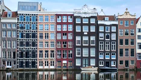 houses-and-boat-on-Amsterdam-canal-Damrak-with-reflection.-Ams