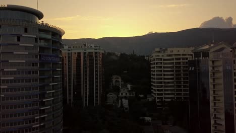 silueta-de-rascacielos-altos-living-pisos-de-edificios-en-un-atardecer-en-cerca-de-las-montañas-y-las-nubes-arriba