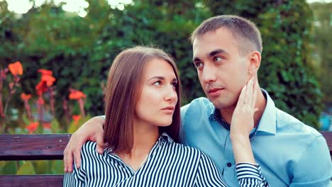 Glückliches-junges-Paar-in-Liebe-sprechen-beim-Sitzen-auf-einer-Parkbank