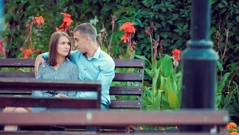 Young-couple-spend-time-together-on-a-bench-in-a-holiday-park