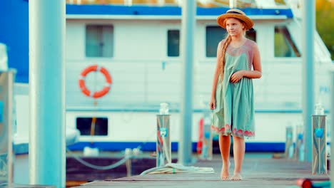 Beautiful-red-haired-child-girl-walks-by-the-pier-for-boats-and-yachts