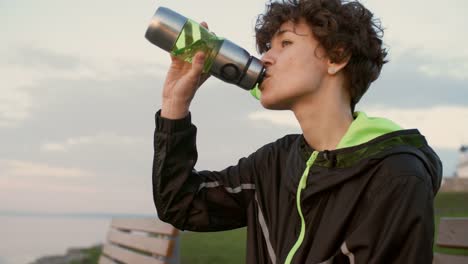 Weibliche-Läufer-Trinkwasser-auf-Uferpromenade