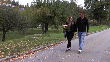 Chico-joven-con-una-chica-caminando-en-el-parque,-cogidos-de-la-mano