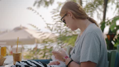 Mother-feeding-baby-from-the-bottle-in-outdoor-cafe