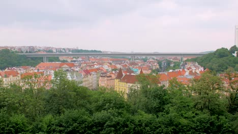 top-view-on-ancient-city-Prague,-red-roofs-and-modern-huge-metal-bridge-over-town