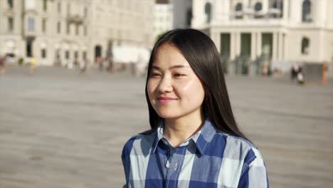 Young-Asian-woman-using-mobile-phone-in-city-streets