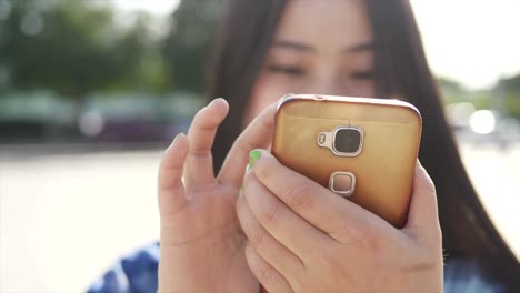 Young-Asian-woman-using-mobile-phone-in-city-streets