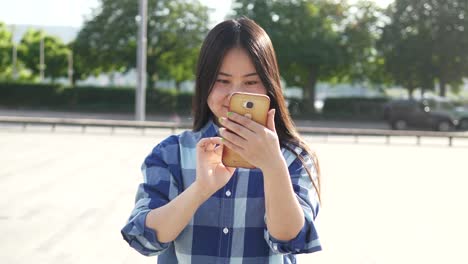 Young-Asian-woman-using-mobile-phone-in-city-streets