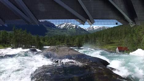 Vuelo-debajo-del-puente-por-encima-de-la-cascada-en-Noruega